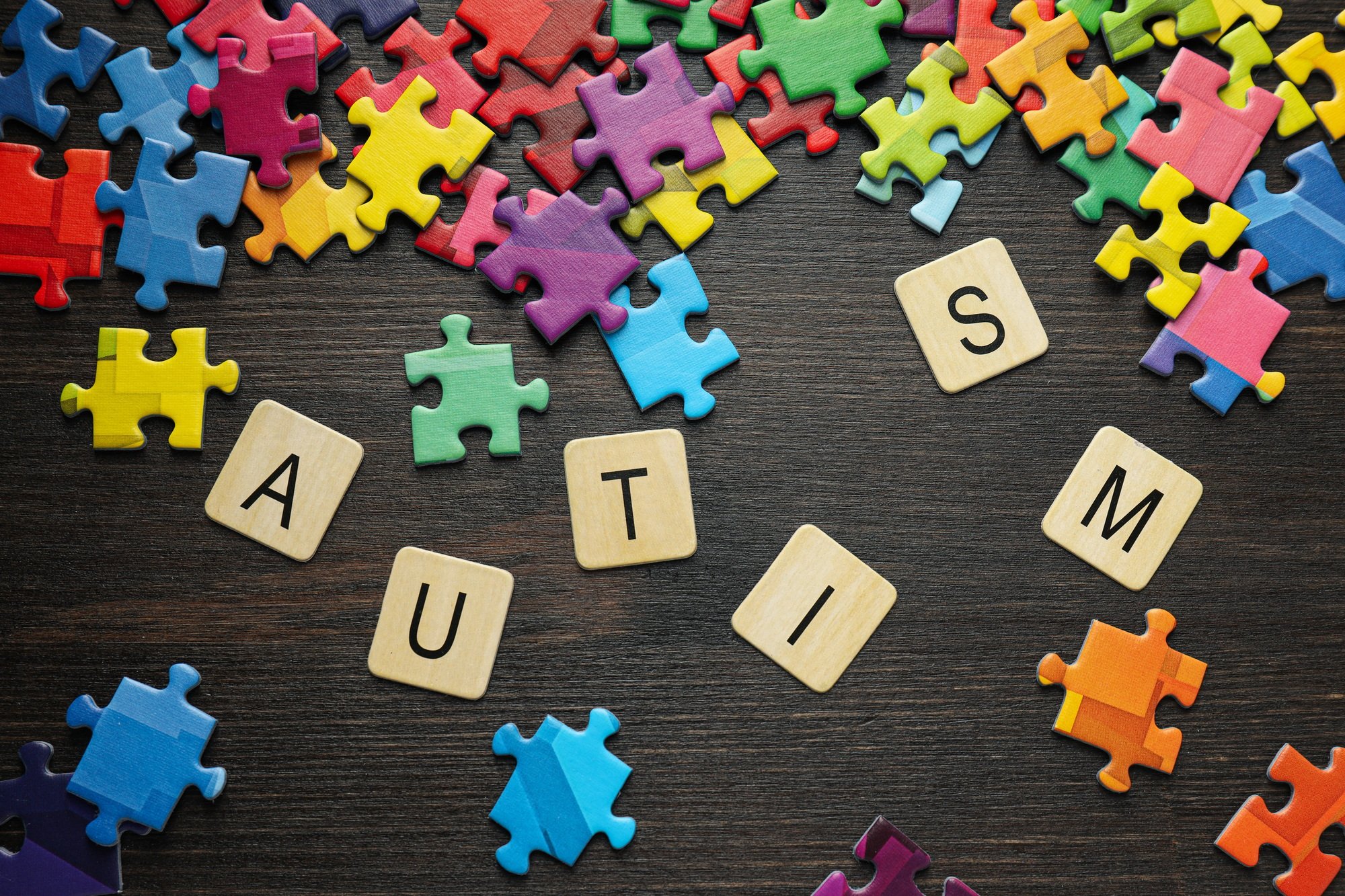 Multicolored puzzle pieces with the word "autism" on a black background. World autism day concept